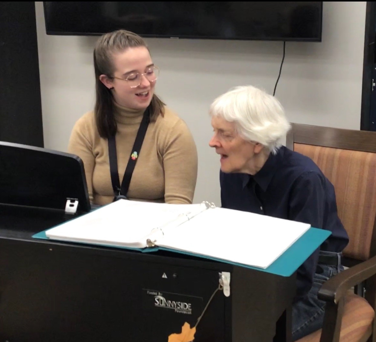 A participant of the overnight stay program singing while a staff member plays the piano.
