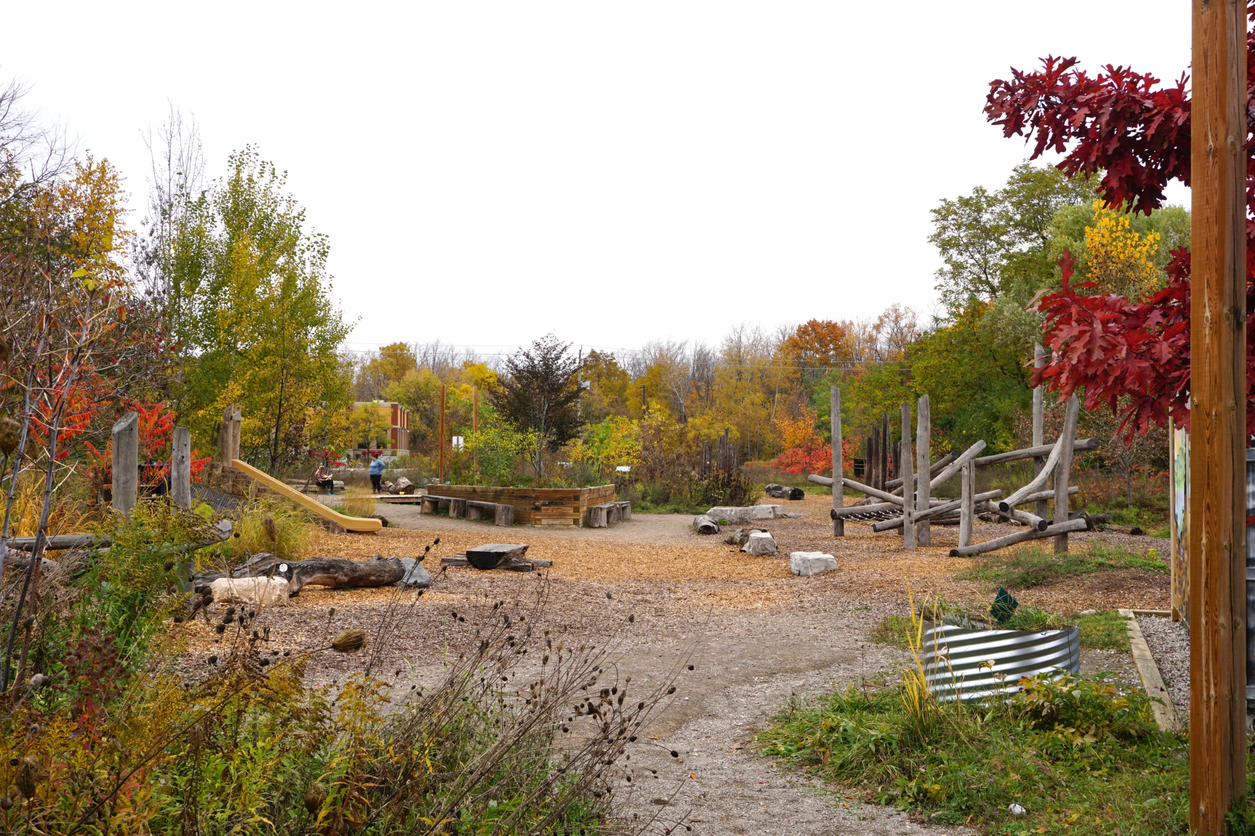 Photo of the natural playground at Huron Natural Area. There are several climbing structures, seats and benches made of wood.