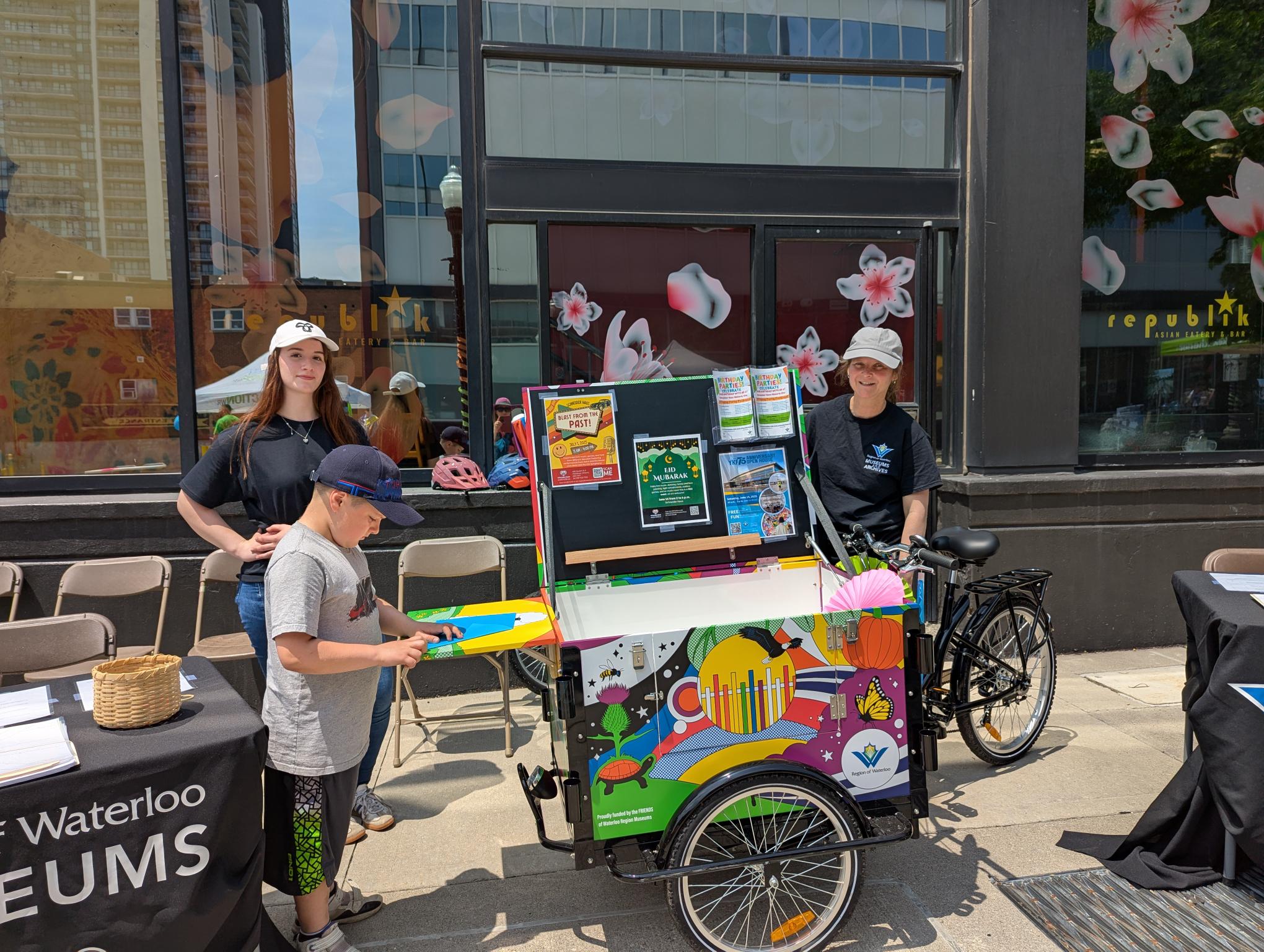 An image of three people interacting with the Museum bike