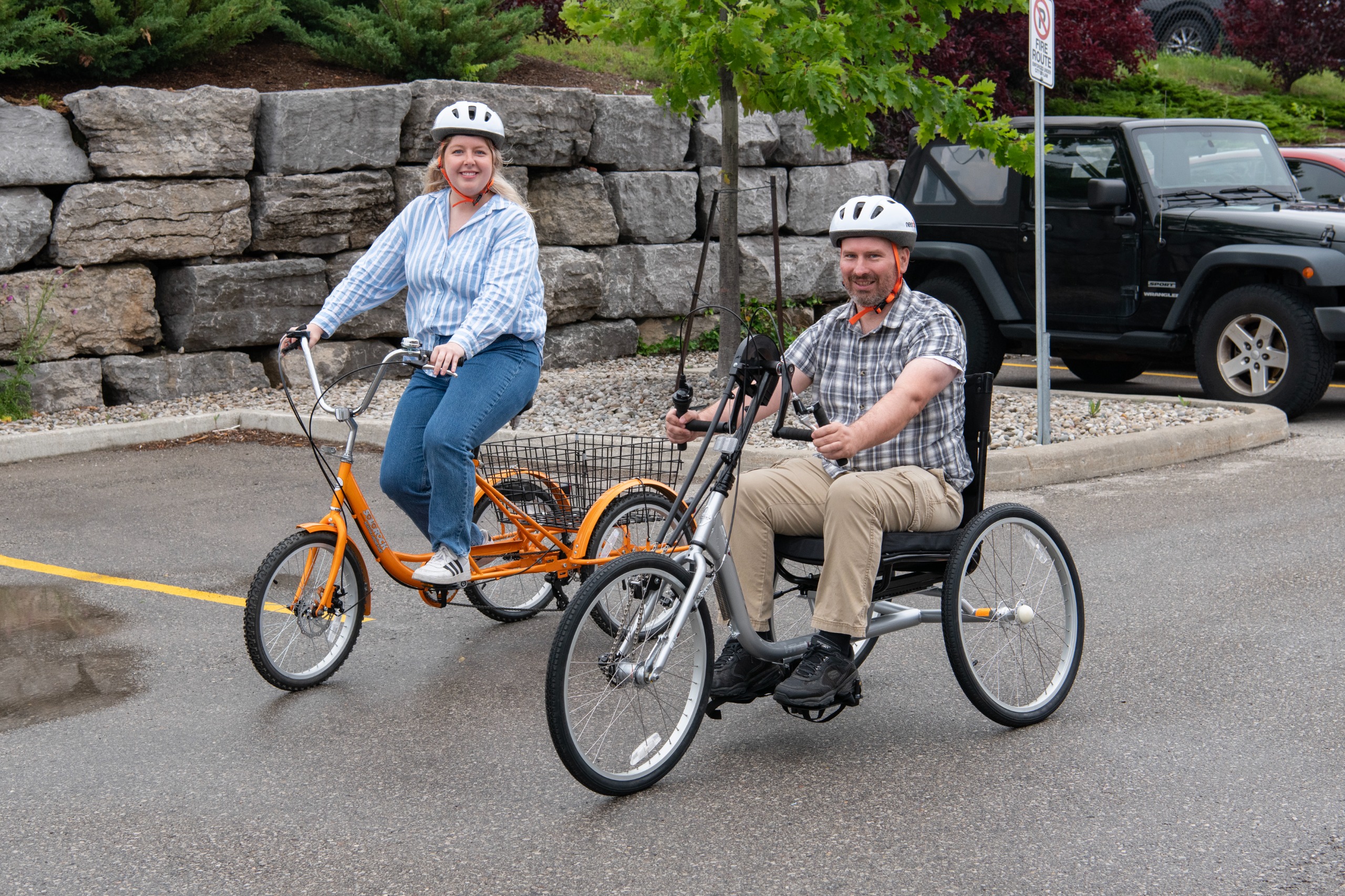 Two people on bikes, one is an accessible handcycle tricycle.
