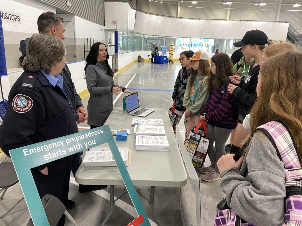 Group of individuals and youth at a display about emergency management.