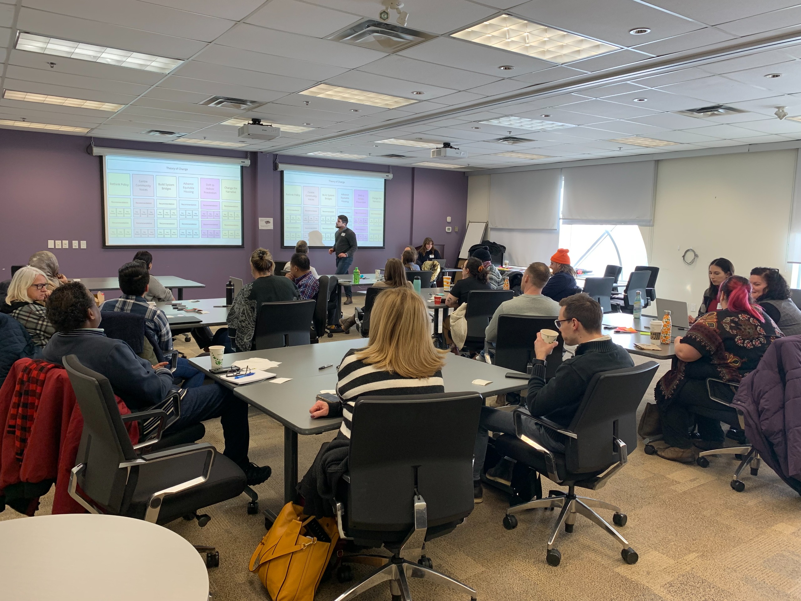 PECH co-creators planning together in small groups around tables. 