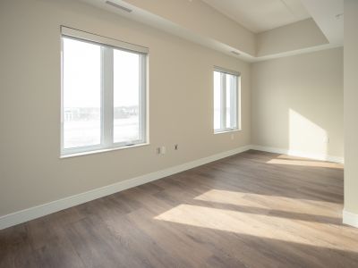 image of a bedroom in one of the 420 Kingscourt units which shows and open room area with eggshell coloured walls and two windows with light shining into the floor