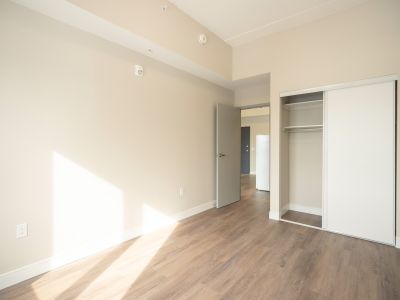 image of a bedroom in one of the 420 Kingscourt units which shows an open closet door beside the bedroom door entrance