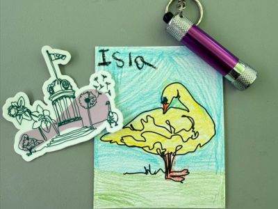​Isla's crayon artwork shows a yellow swan, standing on green grass with blue sky above. The name Isla is signed in the top right corner. ​